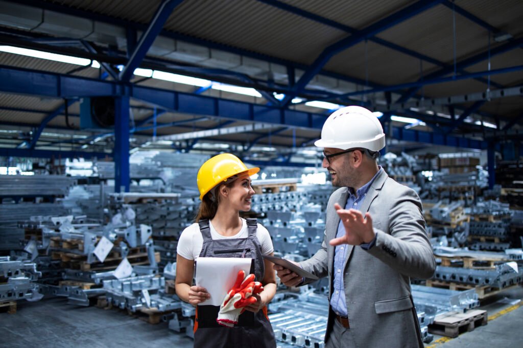 manager wearing hardhat and industrial worker discussing about production in metal factory.